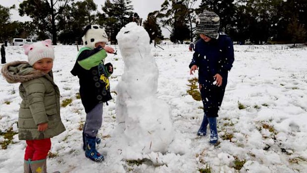 Beau, Noah and Lily Bartolo play with a snowman in a snow covered field in the NSW Southern Highlands town of Mittagong. (AAP)