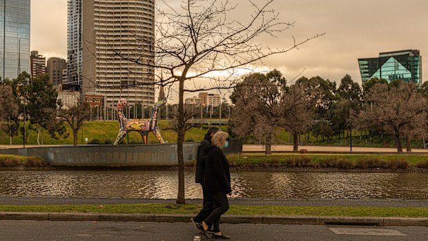 People wearing masks walk along the banks of the Yarra River on August 06, 2020 in Melbourne, Australia.