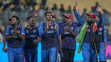 Rashid Khan waves to Afghanistan fans with the country's flag around his neck. 