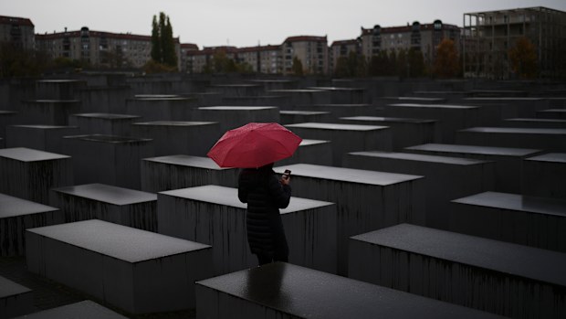 A woman with a red umbrella visits the Memorial for the murdered Jews of Europe, the so called Holocaust Memorial in central Berlin. 