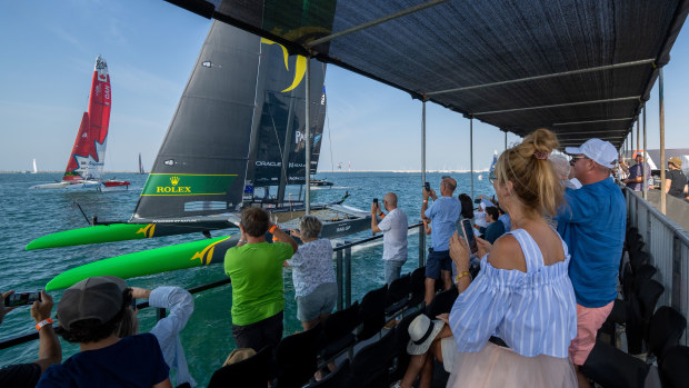 Spectators watch the Australia SailGP team helmed by Tom Slingsby sail closely past the waterfront area on race day one of the Dubai Sail Grand Prix.