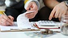 Close-up view of man and woman making account of family income. Writing down and calculating expenses. Attentive review of finance. Calculator on desk. Economy concept