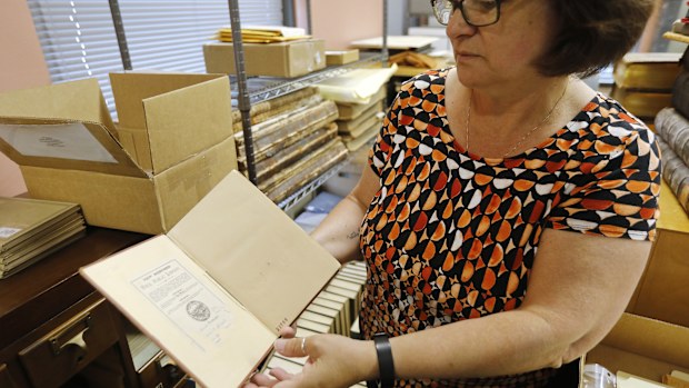 New Bedford Public Library Director Olivia Melo takes a look at the one hundred year overdue book on Friday, July 7, 2023. "An Elementary Treatise on Electricity" by James Clerk Maxwell was returned to the West Virginia University library one hundred years after it was taken out of the New Bedford Public library in 1903.
