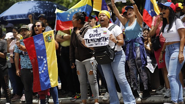 A woman holds a sign with a message that reads in Spanish; "We are not terrorists" as she waits with fellow supporters for the arrival of opposition leader Maria Corina Machado, in Caracas, Venezuela, Saturday, Aug. 3, 2024. (AP Photo/Cristian Hernandez)
