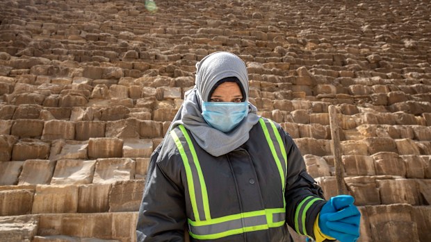 A municipal worker cleans at the Giza Pyramids as a prevention measure due to the coronavirus outbreak, in Giza,  Egypt, Wednesday, March 25, 2020. 