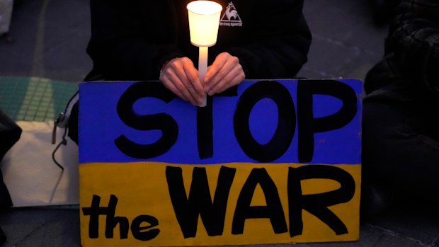 A participant holds a candle during a candle light vigil in support of Ukraine, near the Russia Embassy in Seoul, South Korea, Friday, March 4, 2022
