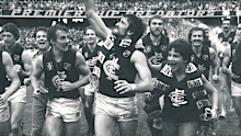 Peter Bosustow, premiership cup in hand and Carlton scarf flowing, leads the triumphant Blues on a victory lap of the MCG following the 1982 VFL grand final.
