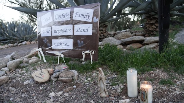 Lit candles next to a sign from neighbors supporting the Guthrie family outside of Nancy Guthries house in the early morning hours of Sunday, Feb. 8, 2026 in Tucson, Ariz. (AP Photo/Ty ONeil)