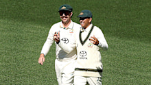 Usman Khawaja celebrates with Travis Head after taking a catch.