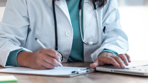 Shot of female doctor working with her computer in medical consultation.