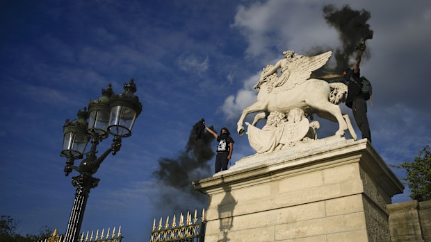 Youth light flares on Place de la Concorde during a protest in Paris, France, Friday, June 30, 2023. French President Emmanuel Macron urged parents on Friday to keep teenagers at home and proposed restrictions on social media to quell rioting spreading across France over the fatal police shooting of a 17-year-old driver. (AP Photo/Lewis Joly)