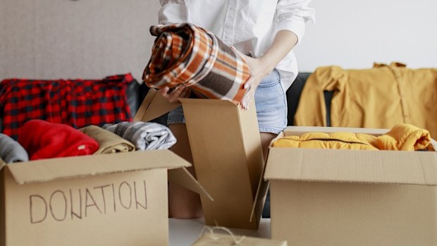 Woman sorting clothing and packing donation box