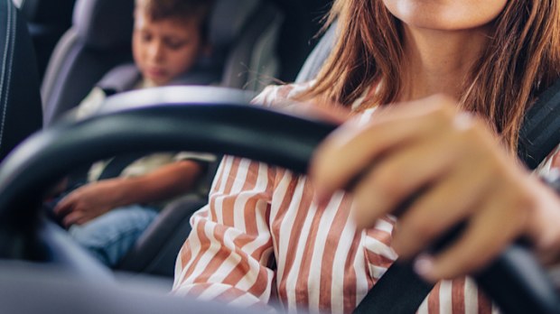 Mother driving her young son to school in a car
