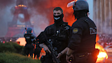 A car burns and fireworks explode as police watch PSG supporters celebrate in Paris.