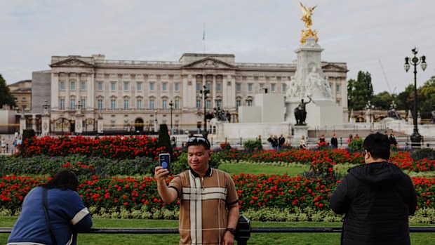 Tourists take photographs in front of Buckingham Palace in London.