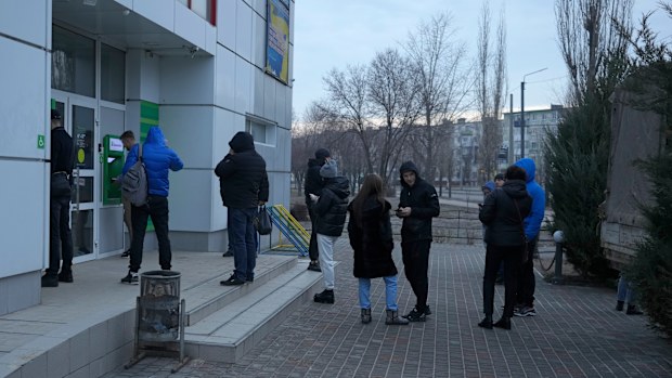 People queue to use an ATM machine outside in Sievierodonetsk, the Luhansk region, eastern Ukraine, Thursday, Feb. 24, 2022. Russian President Vladimir Putin on Thursday announced a military operation in Ukraine and warned other countries that any attempt to interfere with the Russian action would lead to "consequences you have never seen." (AP Photo/Vadim Ghirda)