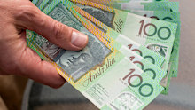 Hand holding australian dollars 100 banknotes on glass table background. Finance and payment concept. MONEY CASH