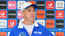 Alastair Clarkson speaks to the media wearing a retro 1996 Kangaroos jacket.