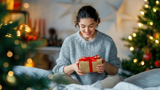 Merry Christmas, Happy Holidays. Surprised happy woman opening a Christmas present.