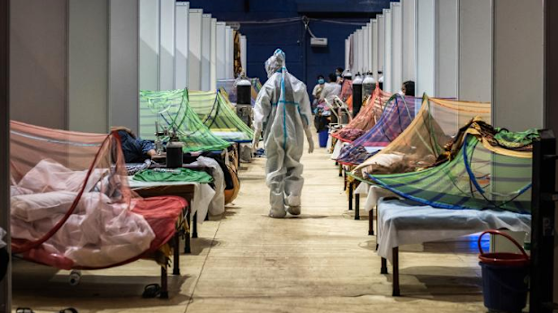 A medical worker observes patients inside a COVID-19 ward that was set up inside a sports stadium in New Delhi.