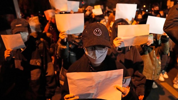 Protesters hold up blank papers and chant slogans as they march in protest in Beijing.