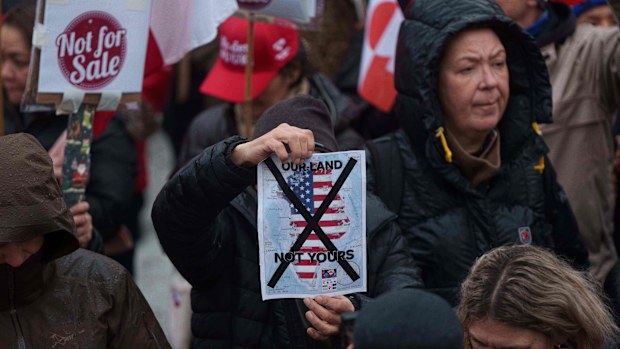 A man holds a map of Greenland covered in the American flag crossed out with an X during a protest against Trump's policy towards Greenland in front of the US consulate in Nuuk, Greenland, Saturday, Jan. 17, 2026.