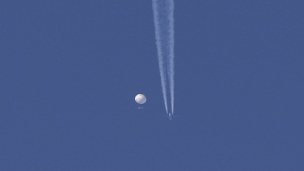 In this photo provided by Brian Branch, a large balloon drifts above the Kingstown, N.C. area, with an airplane and its contrail seen below it. 