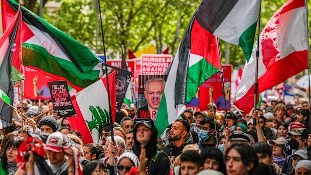 Pro-Palestine protesters waving Palestine flags as a protesters holds a placard of Benjamin Netanyahu on October 06, 2024 in Melbourne, Australia. 