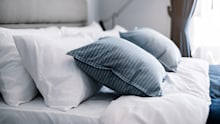 Bed made-up with clean white pillows and bed sheets in beauty room. Close-up. Lens flair in sunlight.