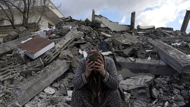A woman sits on the rubble as emergency rescue teams search for people under the remains of destroyed buildings in Nurdagi town on the outskirts of Osmaniye city southern Turkey.