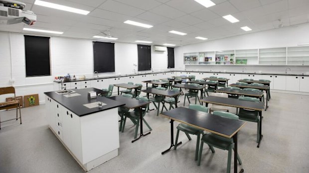 A classroom with white walls and black chairs and desks.