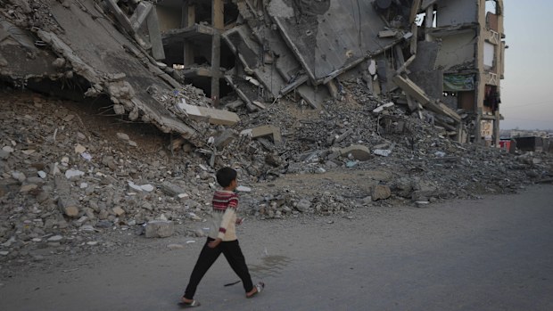 A Palestinian boy walks past a destroyed building at a neighbourhood in Khan Younis, Gaza Strip, Sunday, Dec. 1, 2024.