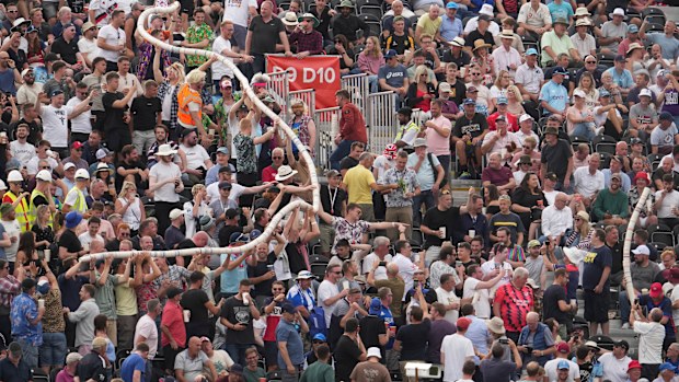 Fans in the stands make a beer snake out of empty plastic pint cups during the second day of the 2nd test cricket match between England and South Africa at the Old Trafford, in Manchester, England, Friday, Aug. 26, 2022.