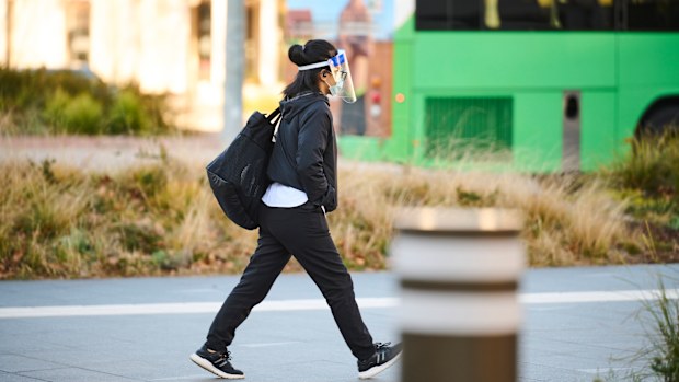 A pedestrian wearing a face shield and mask in Canberra.