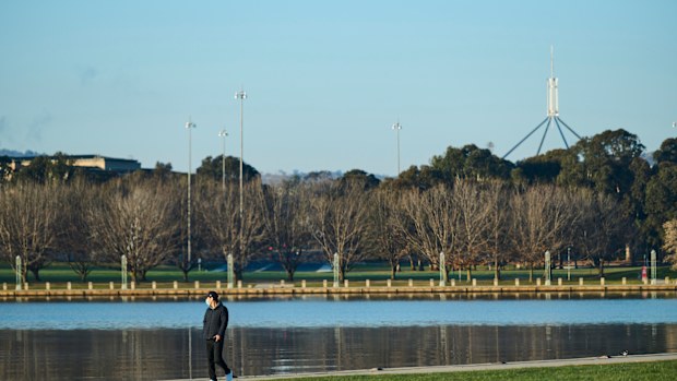 A walker wearing a mask beside Lake Burley Griffin in Canberra.