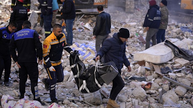 Two men carry a body from a destroyed building in Adana, southern Turkey.
