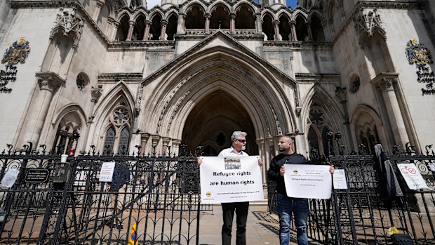 Protestors stand outside The Royal Court of Justice in London, Friday, June 10, 2022. The High Court will hear a legal challenge lodged by Care4Calais, the Public and Commercial Services Union (PCS) and Detention Action, opposing the Home Office's new asylum deal with Rwanda. The case alleges that Priti Patel's proposals are in contravention of international law and the UN refugee convention. (AP Photo/Frank Augstein)