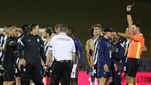 The referee shows a red card after players scuffle.