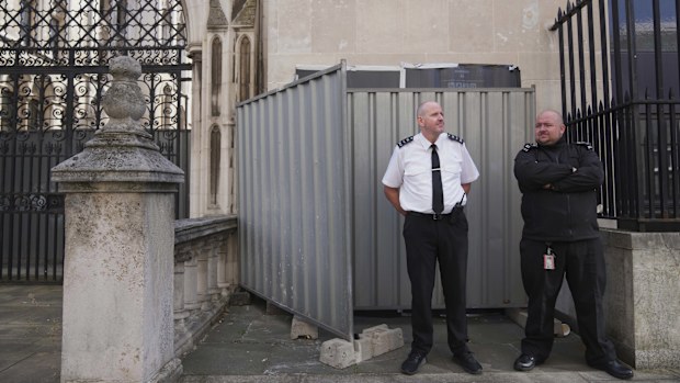 Security officials stand in front of large sheets of black plastic and two metal barriers which conceal street artist Banksy's latest artwork.