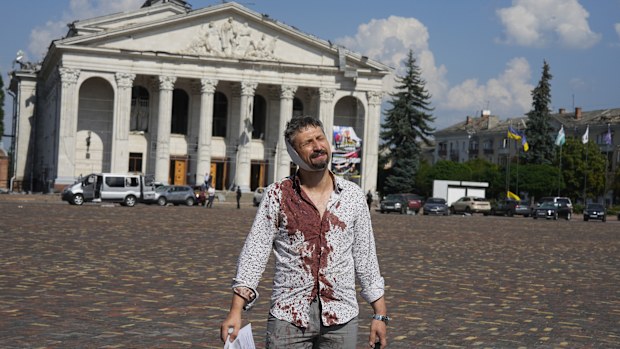 An injured man walks in Krasna square with the Taras Shevchenko Chernihiv Regional Academic Music and Drama Theatre in the background, after a Russian attack, in Chernihiv, Ukraine.
