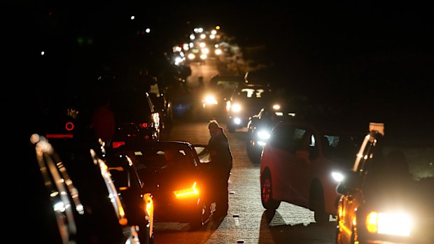 Motorists make their way along as people search for a vantage point of the erupting Mauna Loa volcano, Friday, Dec. 2, 2022, near Hilo, Hawaii.