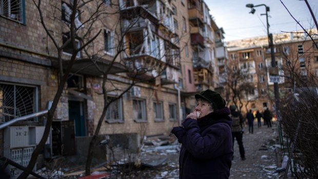 A woman looks at residential buildings damaged by a bomb in Kyiv, Ukraine, Friday, March 18, 2022. 