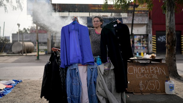 A vendor holds up secondhand garments.