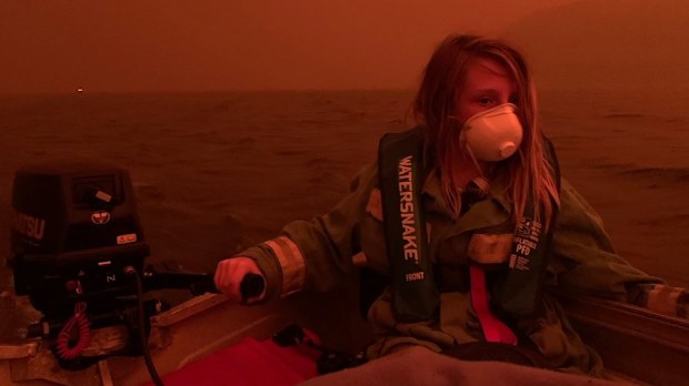 Finn Burns navigates a boat through thick smoke at Mallacoota, as fire advanced on the seaside Victorian town on December 31, 2019.
