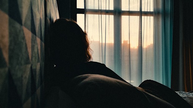 woman sitting on bed in front of window