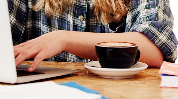 Woman using computer while drinking coffee