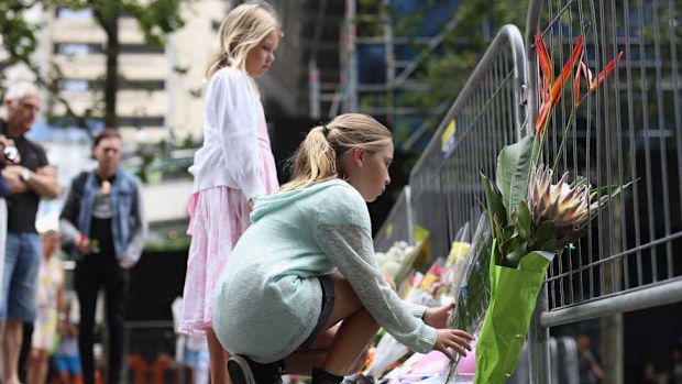 A young girl places flowers at the site of the Sydney siege that claimed two innocent lives.