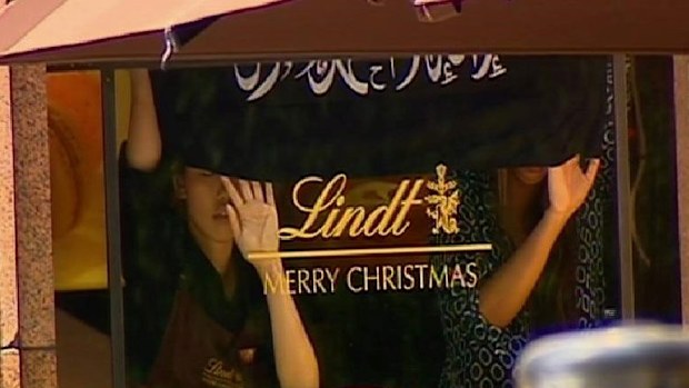Hostages hold up a black flag with Arabic writing inside the Lindt cafe. (supplied)