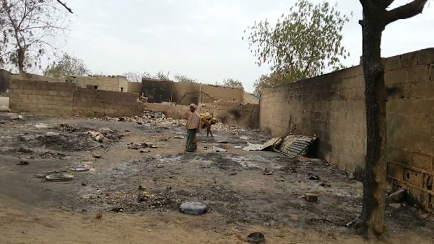 A young girl stands amid the burned ruins of Baga, Nigeria. (AAP)
