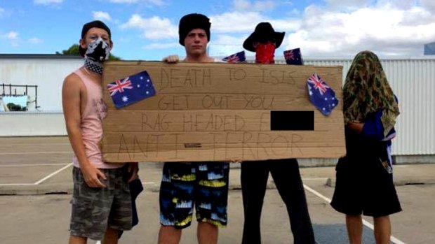 Men stood on top of a Townsville shopping centre holding a racist sign in the wake of the Sydney siege.